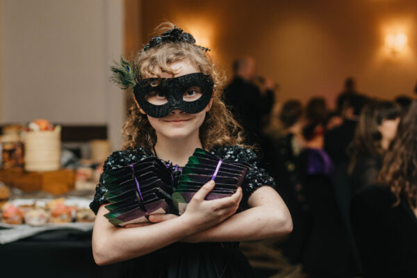 Child wearing masquerade mask at gala event